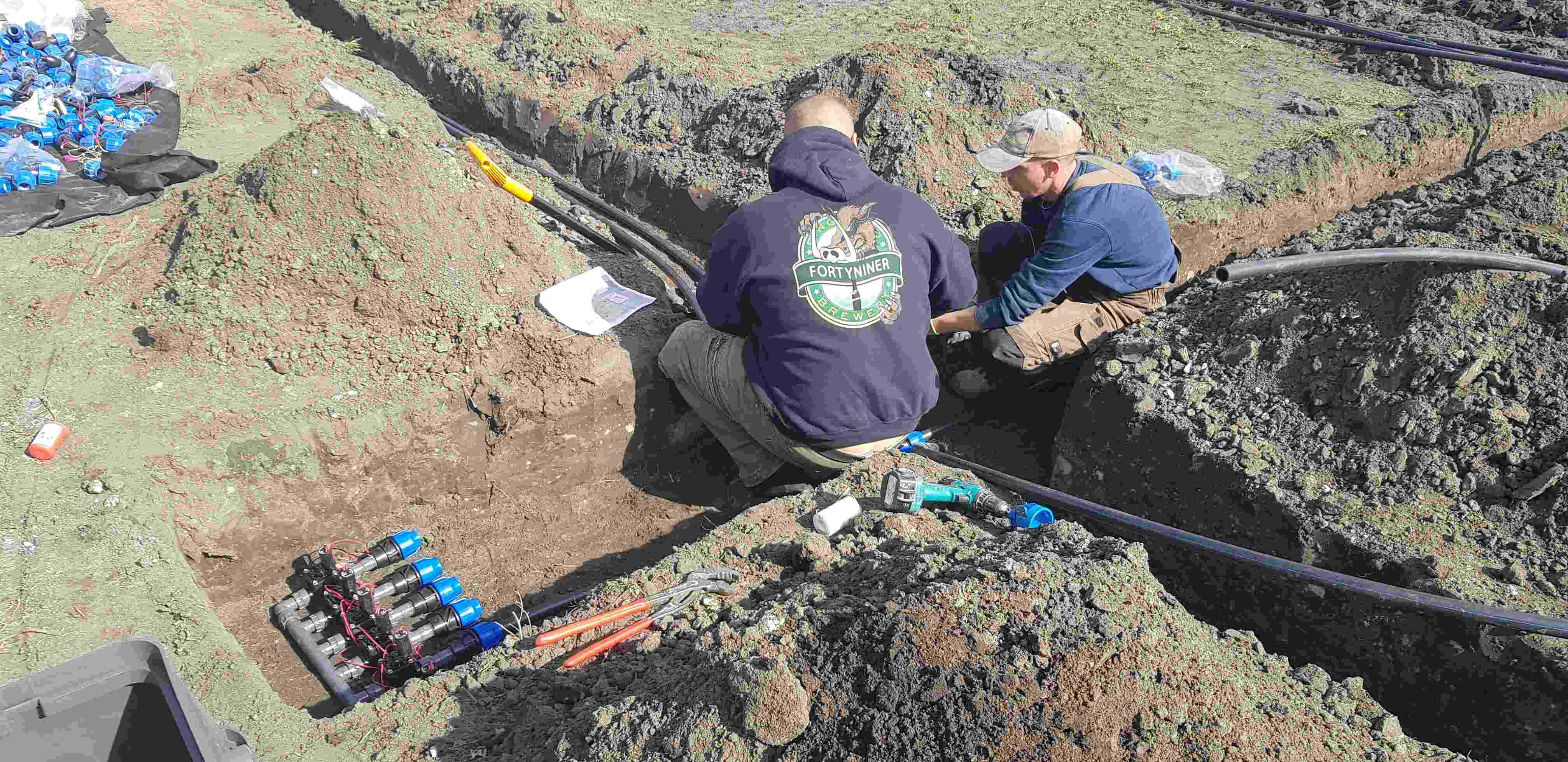 Pracovníci pri ukladaní potrubia a montáži závlahového systému do výkopu