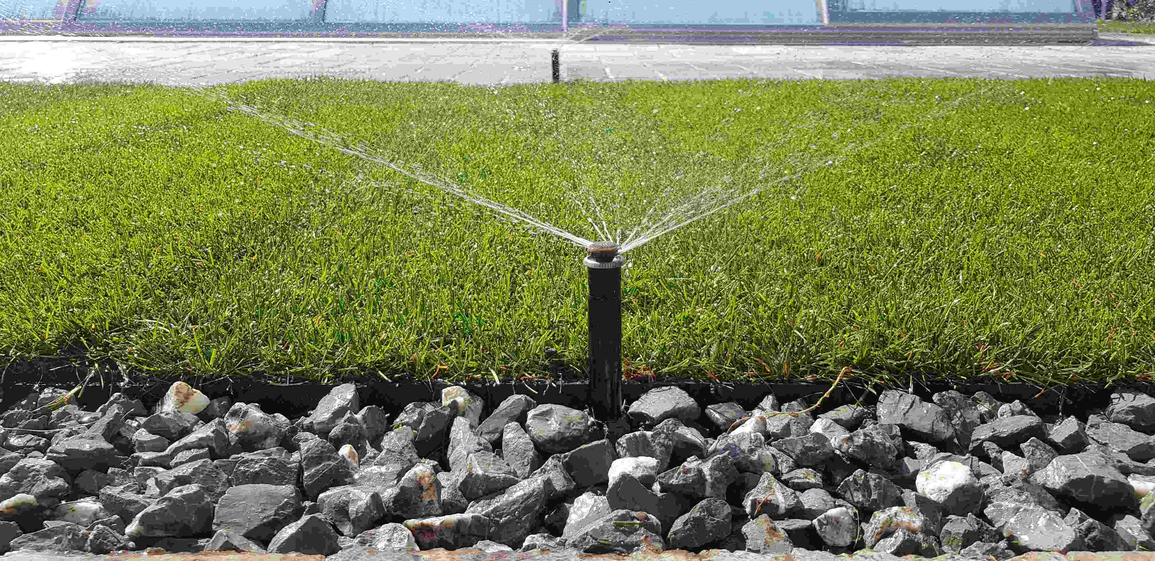 Výsuvný postrekovač v akcii na rozhraní trávnika a okrasného kamenistého záhona